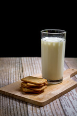 Fresh milk in glass serve with square of cracker on wooden tray with copy space for your text. Healthy beverage concept.