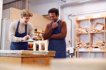 Tutor With Male Carpentry Student In Workshop Studying For Apprenticeship At College