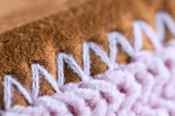 Close background of pink knitted sock with brown velour soles. Cute winter room slippers. Macro of pink and brown rib pattern wool cloth. Handmade pink and brown knit warm sock close up.