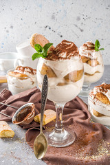 Traditional italian dessert tiramisu. Many glasses with homemade tiramisu with chocolate cocoa powder, grey stone stone or concrete background.