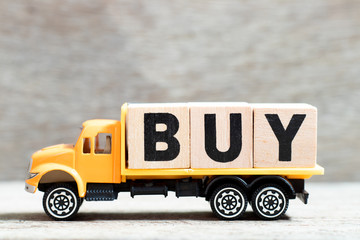 Fototapeta premium Truck hold letter block in word buy on wood background
