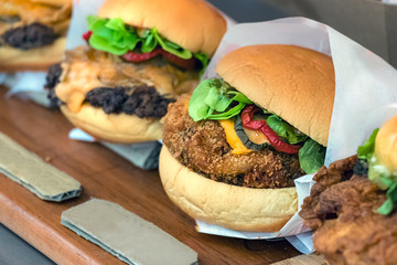 Chicken burgers placed in row on a restaurant counter.