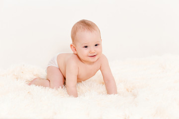 Europoid cute baby crawls on a fluffy blanket at home. baby in one diaper.