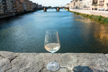Obraz premium Lonely wine glass in distance from people, on bridge of Florence, Italy. Empty european city