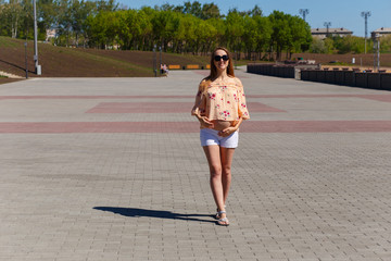 a Caucasian thirty year old pregnant woman in short white shorts walks on the pavement