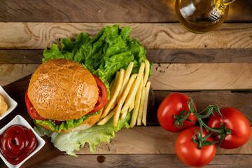 Hamburger,onion rolls and fried potatoes with sauces and tomatoes, top view