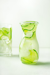 Cucumber infused water in glass jar and highball glass with copy space