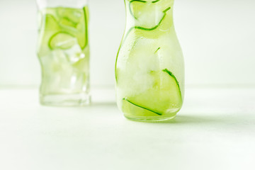 Cucumber water in glass jar and highball glass, closeup view, with copy space