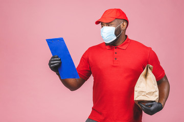 Delivery man employee in red cap blank t-shirt uniform face mask gloves hold empty cardboard box isolated on pink background. Service quarantine pandemic coronavirus virus 2019-ncov concept.