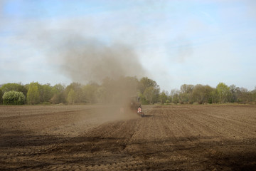 Traktor mit Pflug auf, durch Dürre / Trockenheit, staubigen Acker vom Betrachter wegfahrend