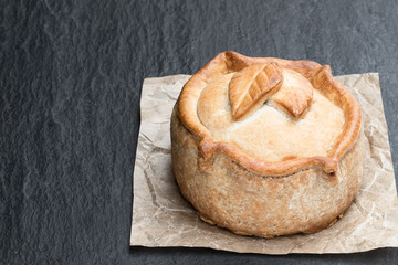 Seasoned cured pork and ham pie on black stone background