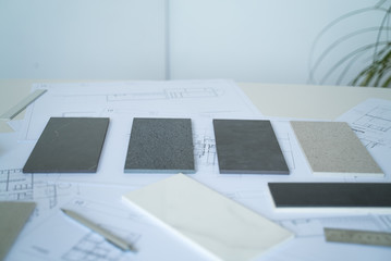 The interior designer selects ceramic stoneware and marble samples. Designer at work. Interior design. Architecture. Decoration. Design project blueprints. Grey marble. Grey stone. Decorative material