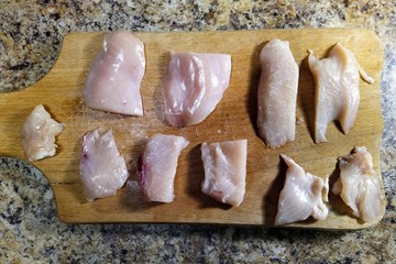 pieces of chicken fillet on cutting board on table