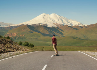 Man Riding on skateboard on Road to Elbrus, Highest Mount in Europe.