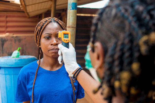 young black lady using a handheld infrared thermometer to test a lady's temperature