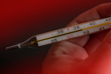 Thermometer in a hand. Temperature measuring by a thermometer. Fever measuring.