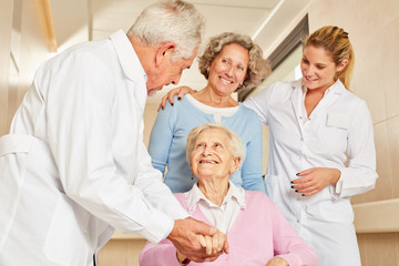 Arzt in Reha Klinik hält die Hand einer Seniorin