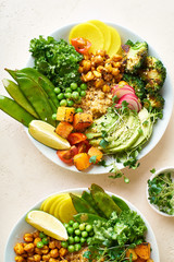 Healthy vegetarian lunch bowl with avocado, chickpeas, quinoa and vegetables, garnished with microgreens and nut dressing. Flat lay on stone background.