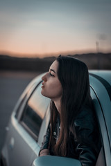 A young woman leaning over the window of a gray car