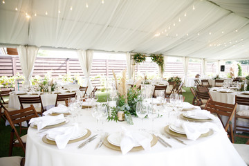 banquet table is decorated with plates, cutlery, glasses, candles and flower arrangements