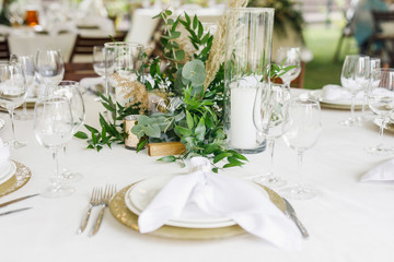 banquet table is decorated with plates, cutlery, glasses, candles and flower arrangements