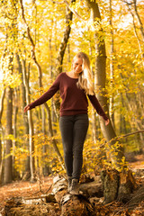 Blonde Frau balanciert auf einem Baumstamm