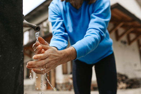 woman wash and sanitize her hands in a fountain in the yard before come back home to prevent infection diseases.