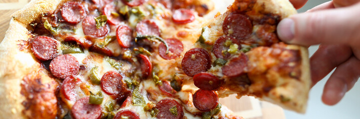 Male hand holding big piece of tasty fresh pizza