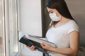 Female doctor in white t-shirt and white mask reviewing documentation