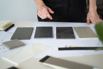 The interior designer selects ceramic stoneware and marble samples. Designer at work. Interior design. Architecture. Decoration. Design project blueprints. Grey marble. Grey stone. Decorative material