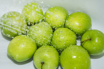 Washing fruit. Wet apples in the shower and water drops. Girl washes fruits and vegetables for the prevention of coronavirus covid-19 2019-ncov