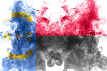 The national flag of the US state North Carolina in against a gray smoke on the day of independence in different colors of blue red and yellow. Political and religious disputes, customs and delivery.