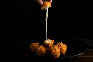 Mozzarella cheese breaded in a black background dish