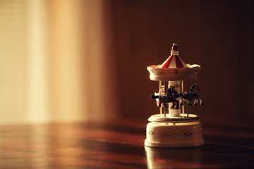 Toy carousel on a wooden table in the rays of daylight © Ольга Юрина