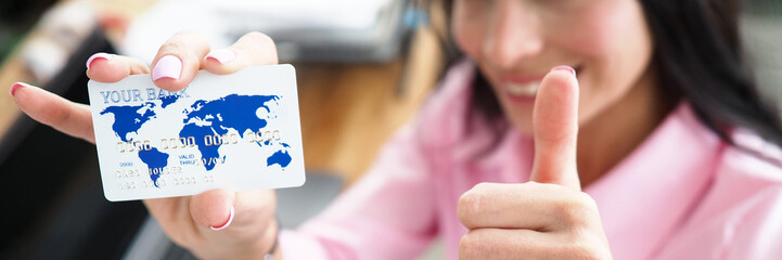 Obraz na płótnie Canvas Girl in office shows bank card and ok gesture