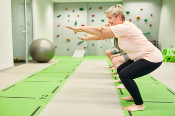Group of vital seniors doing squats