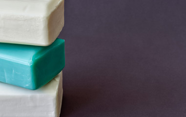 Three pieces of soap of different colors, green and white on a gray background. Hygiene. Purity. Close up. Copy space.