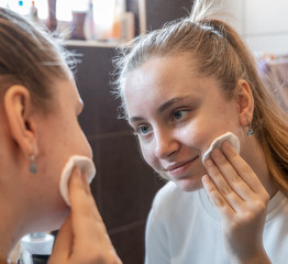  Teen girl wiping her face with a cotton pad