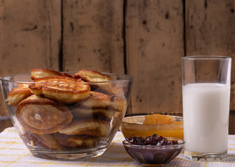 Pancakes on a plate, milk in a glass, jam and honey on a napkin on the table.