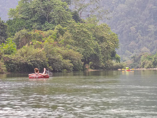 Fototapeta na wymiar Tourist swimming in the green river in the mountains
