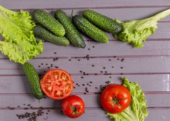 Fresh tomatoes, cucumbers, lettuce and peppers are on the table.