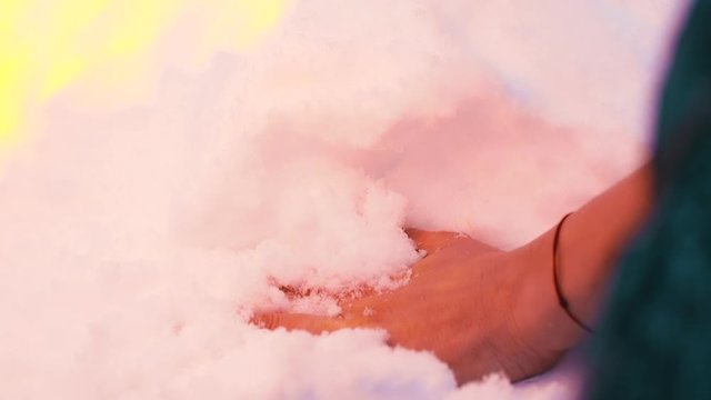 CU, slow motion: middle aged lady hand with thread touches white snow near burning yellow fire in winter wood extreme closeup