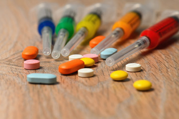 Concept of treatment options for COVID virus infection. Colorful syringes and tablets close-up.