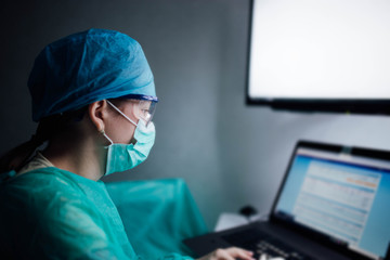 Young girl intern doctor working at night in uniform with a computer in a medical office. Overtime...