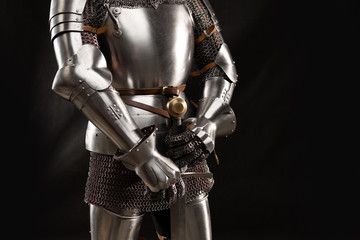 Mannequin man with a beard in a helmet and armor of a knight posing on a black background