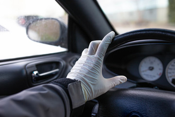 driver's hands in medical gloves on the steering wheel, driver safety in a pandemic.
