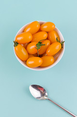 Yellow-orange tomatoes in a bowl on blue background