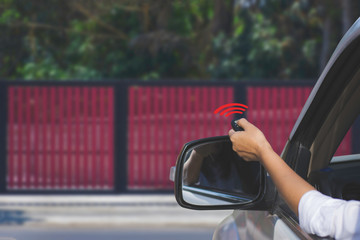 Woman in car, hand opening the automatic gate by using remote control. The auto door and security...