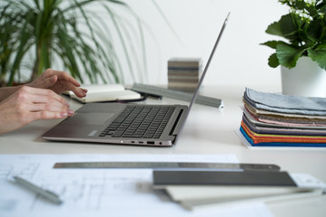 The interior designer sworks behind a laptop. Designer at work. Architect desk. Decoration. Design project blueprints. Plans and drawings. Grey stone. Decorative material. Flatlay. Work from home. 