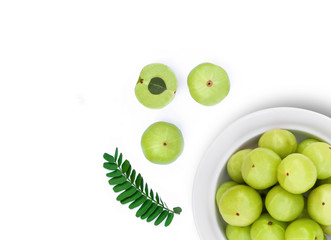 Closeup Indian gooseberry fruits ( phyllanthus emblica, amla ) in wooden bowl with green leaf and sliced isolated on white background. Top view. Flat lay.